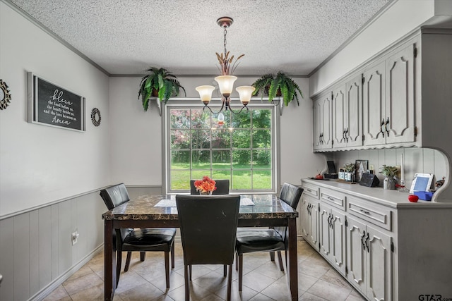 dining area featuring a textured ceiling, ornamental molding, and wainscoting