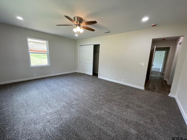 unfurnished bedroom featuring ceiling fan, dark colored carpet, and a closet