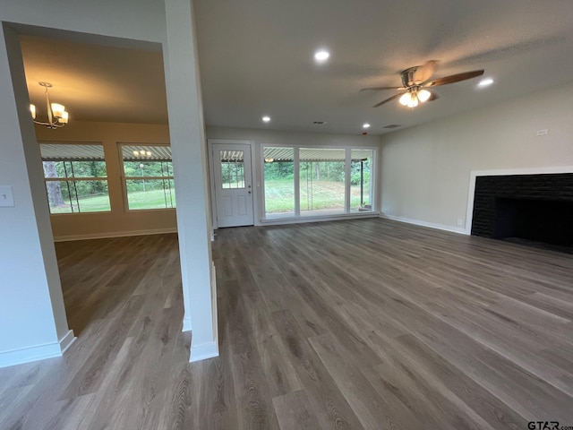 unfurnished living room featuring hardwood / wood-style floors and ceiling fan with notable chandelier