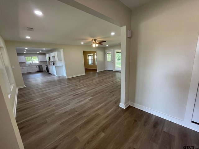 unfurnished living room featuring dark wood-type flooring, ceiling fan, and sink