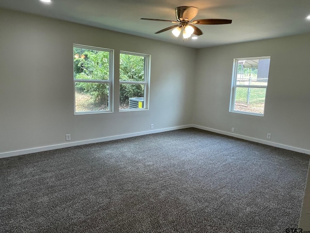 spare room with dark carpet, ceiling fan, and plenty of natural light