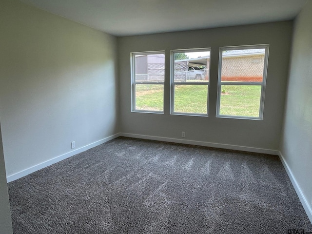 spare room featuring dark colored carpet