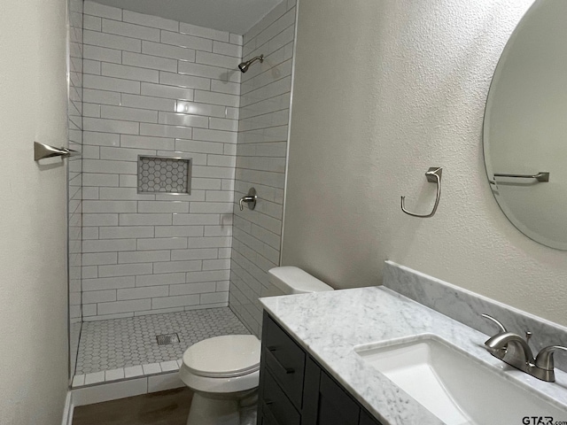 bathroom with toilet, vanity, and a tile shower