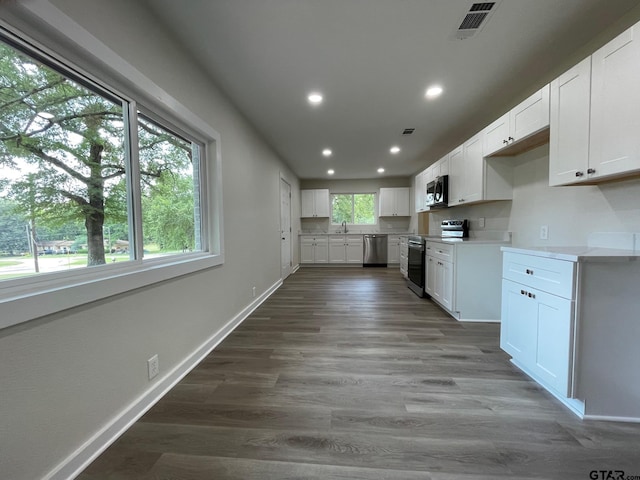 kitchen with white cabinets, stainless steel appliances, sink, and dark hardwood / wood-style flooring