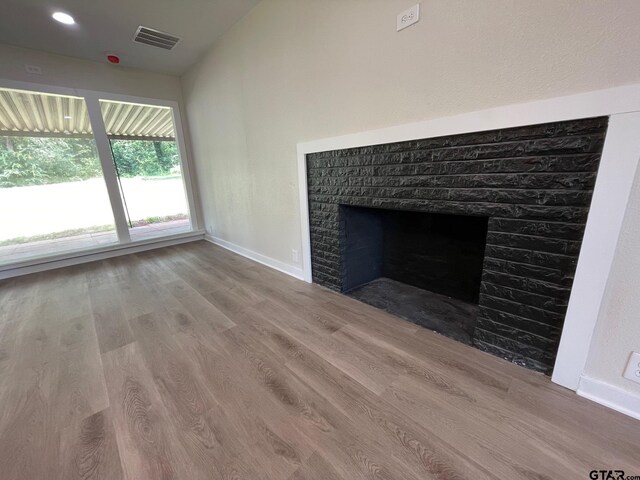 unfurnished living room with a fireplace, hardwood / wood-style flooring, and vaulted ceiling