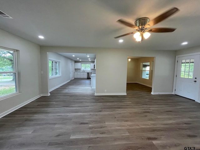 unfurnished living room with dark wood-type flooring, ceiling fan, and a healthy amount of sunlight