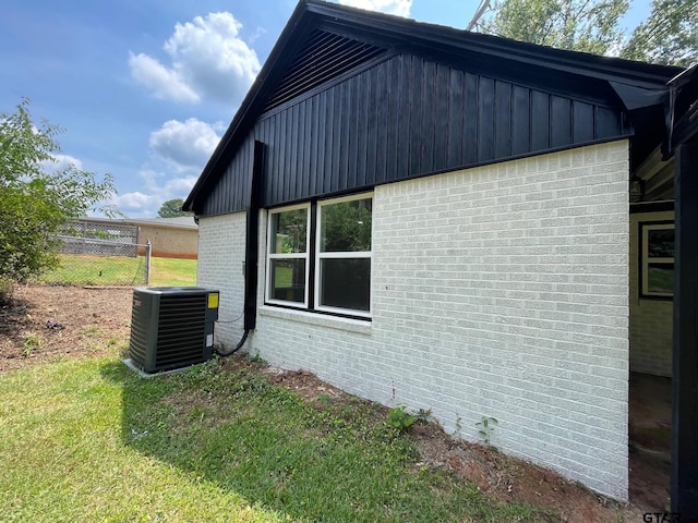 view of side of home with a lawn and central AC