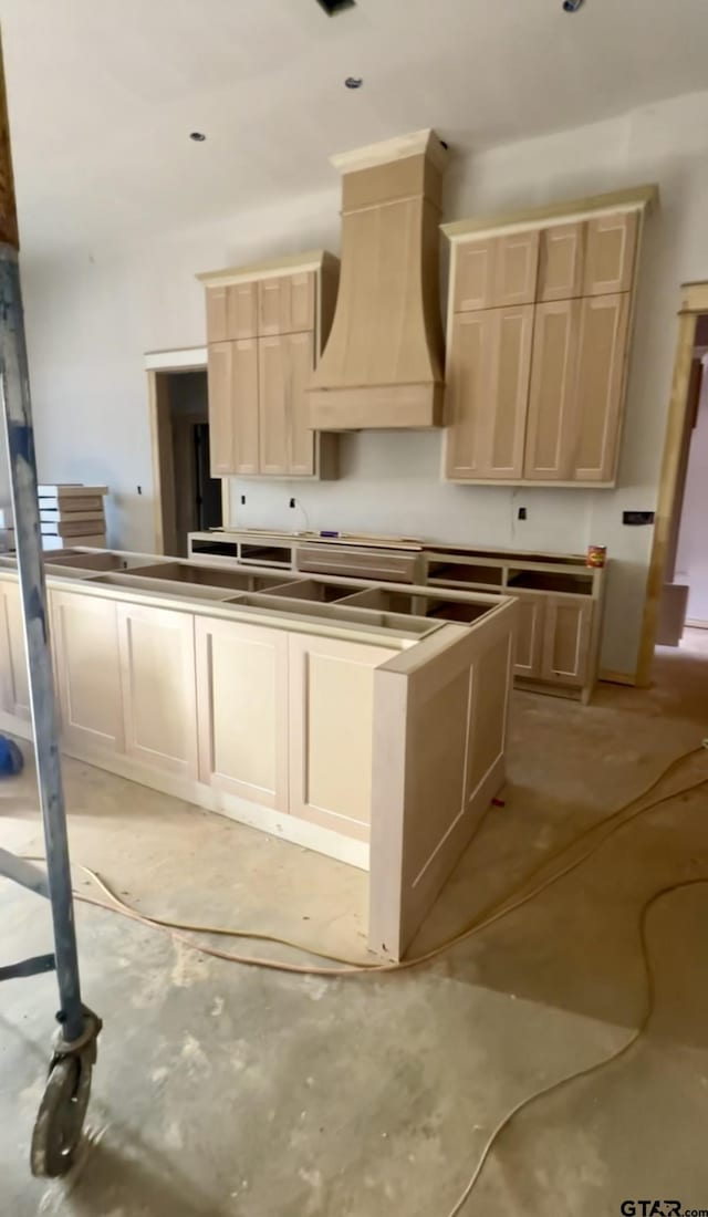 kitchen with light brown cabinetry and custom range hood