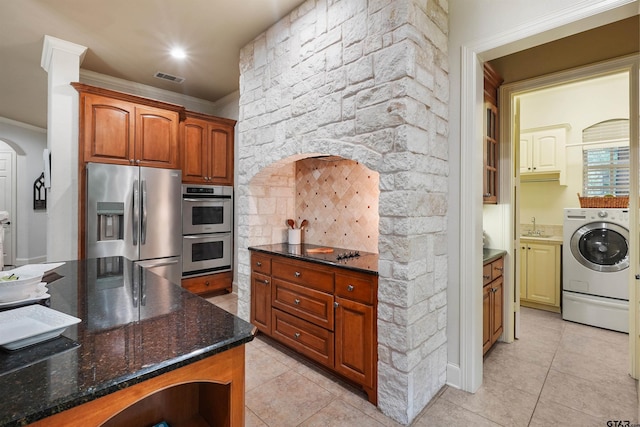 1940 Stonehill Dr, Tyler, TX 75703 - kitchen featuring stainless steel appliances, washer / dryer, light tile patterned flooring, arched walkways, and ornamental molding