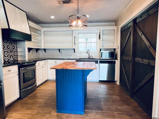 kitchen with stainless steel appliances, hanging light fixtures, a kitchen island, white cabinetry, and range hood