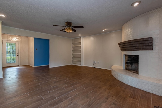 unfurnished living room with ceiling fan, a textured ceiling, dark hardwood / wood-style floors, and a brick fireplace