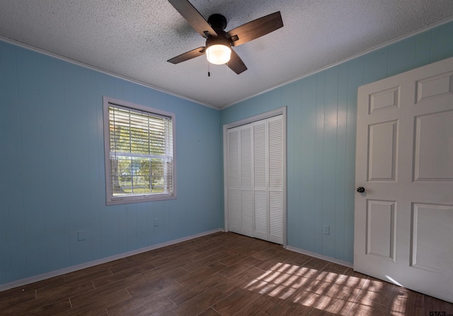 unfurnished bedroom featuring a textured ceiling, ornamental molding, dark hardwood / wood-style floors, ceiling fan, and a closet