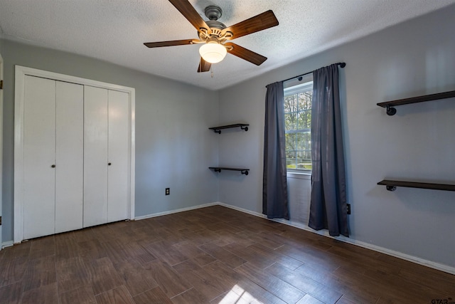 unfurnished bedroom featuring a textured ceiling, ceiling fan, dark hardwood / wood-style floors, and a closet