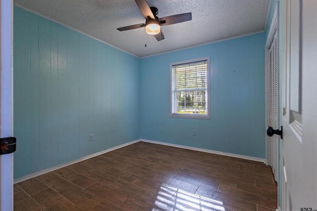 unfurnished room with ornamental molding, a textured ceiling, dark hardwood / wood-style floors, wood walls, and ceiling fan