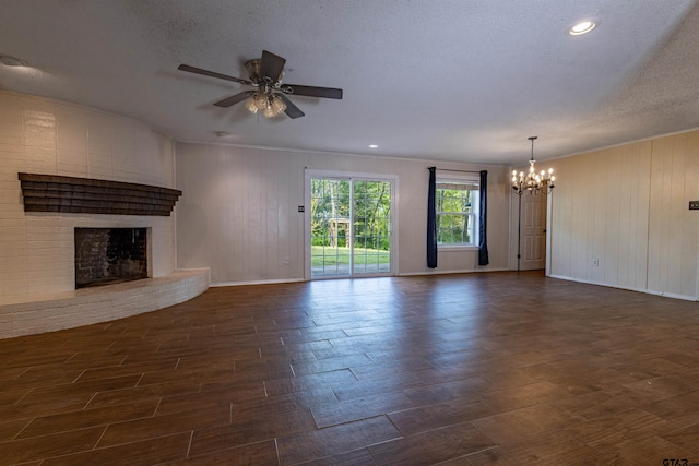 unfurnished living room with dark hardwood / wood-style flooring, a fireplace, a textured ceiling, and ceiling fan with notable chandelier