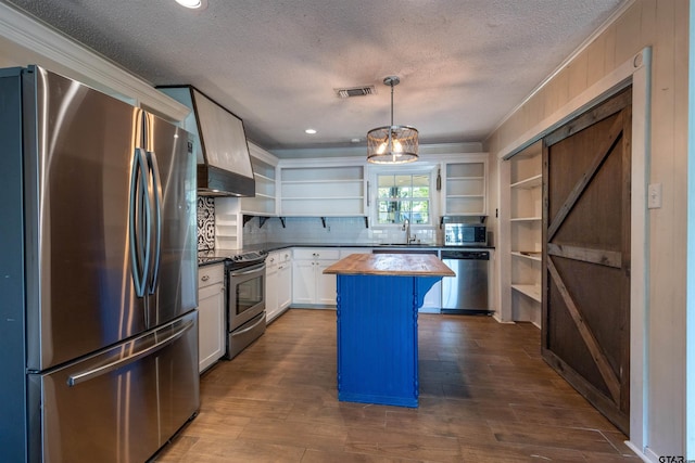 kitchen featuring stainless steel appliances, white cabinets, hanging light fixtures, dark hardwood / wood-style floors, and a kitchen island