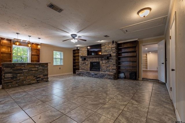 unfurnished living room featuring a fireplace, built in features, a textured ceiling, and crown molding