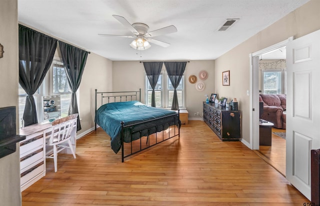 bedroom with light wood-style floors, visible vents, baseboards, and multiple windows