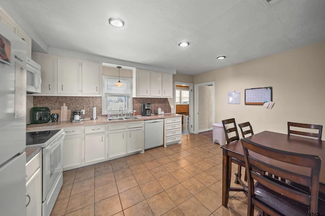 kitchen with tasteful backsplash, light countertops, white cabinetry, a sink, and white appliances