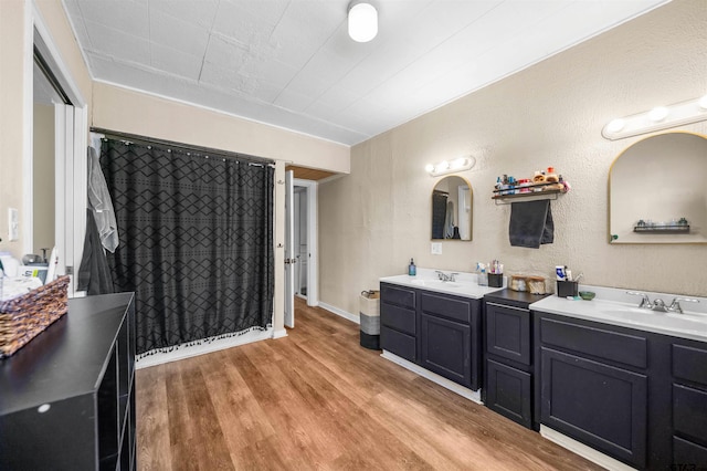 bathroom featuring double vanity, curtained shower, a sink, and wood finished floors