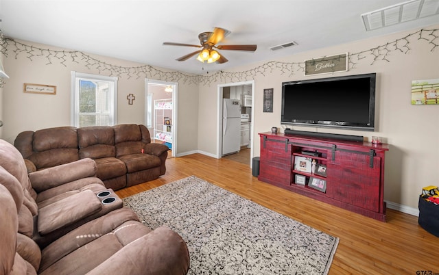 living room with a ceiling fan, visible vents, and wood finished floors