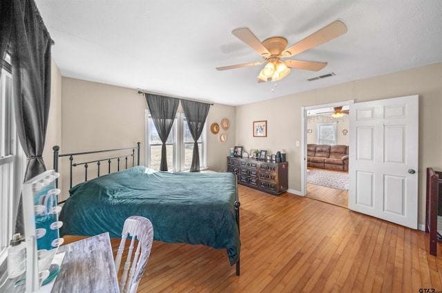 bedroom featuring ceiling fan, light wood finished floors, visible vents, and baseboards