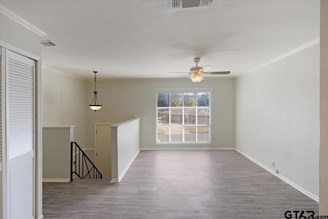 empty room with ceiling fan, wood-type flooring, and ornamental molding