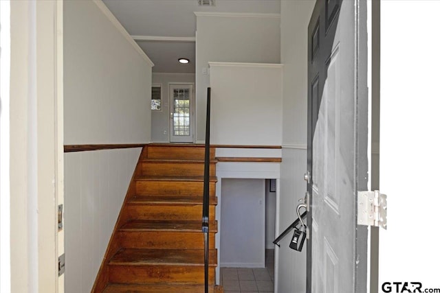 stairway with ornamental molding, tile patterned flooring, and wood walls