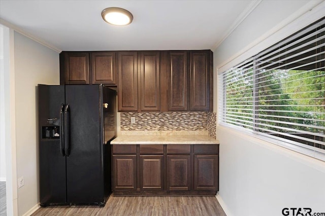 kitchen featuring black refrigerator with ice dispenser, decorative backsplash, dark brown cabinetry, and crown molding