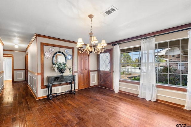 foyer entrance with dark hardwood / wood-style flooring, crown molding, and a chandelier