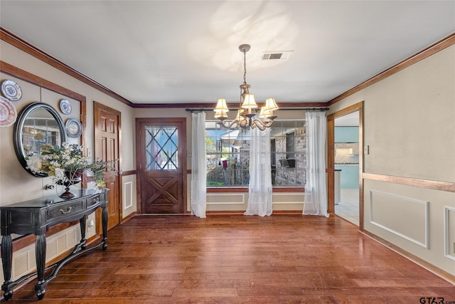 foyer entrance featuring crown molding, dark hardwood / wood-style flooring, and an inviting chandelier