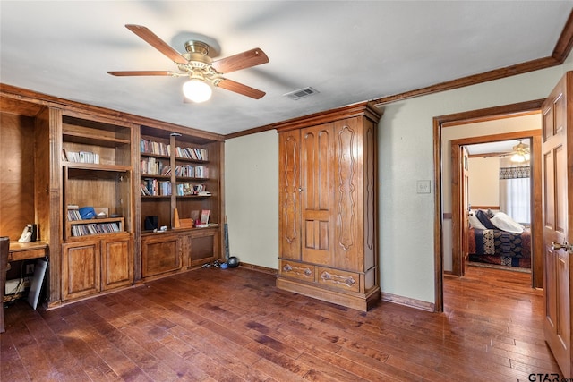 home office with dark wood-type flooring, built in features, and crown molding