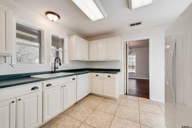 kitchen with visible vents, white appliances, dark countertops, and light tile patterned flooring