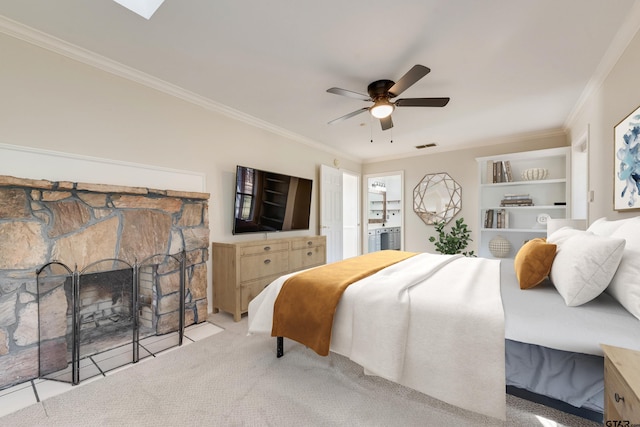 carpeted bedroom with visible vents, a ceiling fan, a stone fireplace, and crown molding