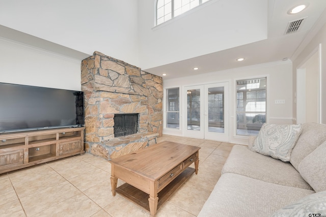 living area featuring tile patterned floors, visible vents, a fireplace, and crown molding