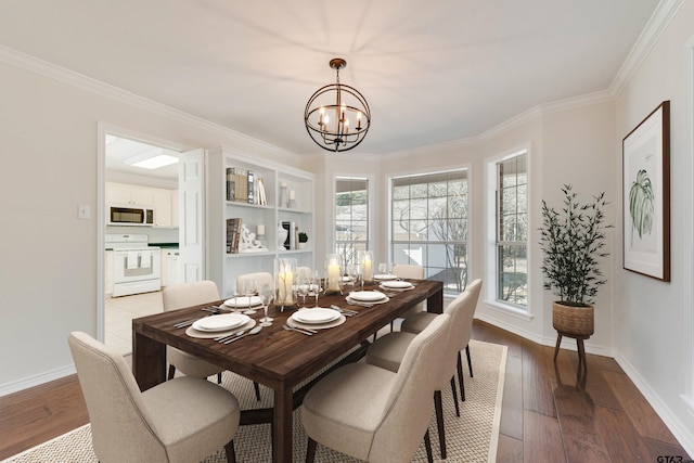 dining area with hardwood / wood-style floors, an inviting chandelier, baseboards, and ornamental molding