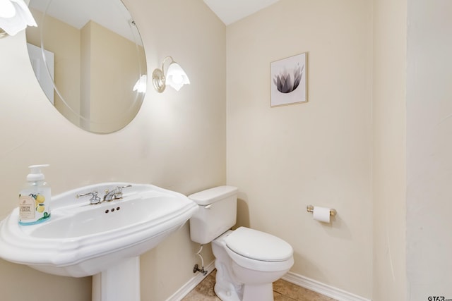 half bath featuring tile patterned flooring, toilet, baseboards, and a sink