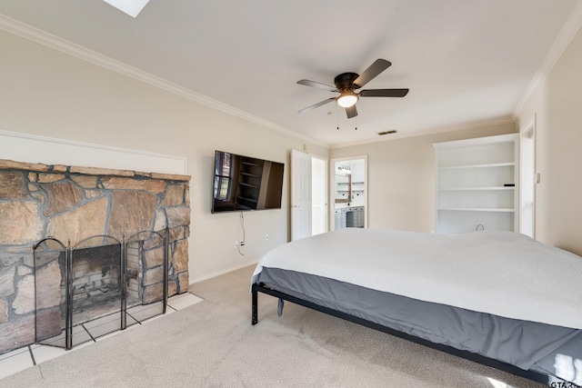 carpeted bedroom with visible vents, baseboards, ceiling fan, ornamental molding, and a stone fireplace