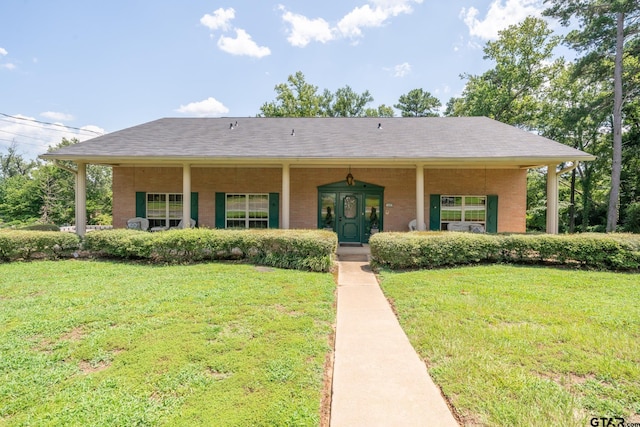 view of front of home featuring covered porch, a front lawn, roof with shingles, and brick siding