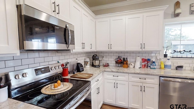 kitchen with tasteful backsplash, appliances with stainless steel finishes, crown molding, and white cabinetry