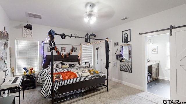 carpeted bedroom featuring visible vents, connected bathroom, baseboards, and a barn door