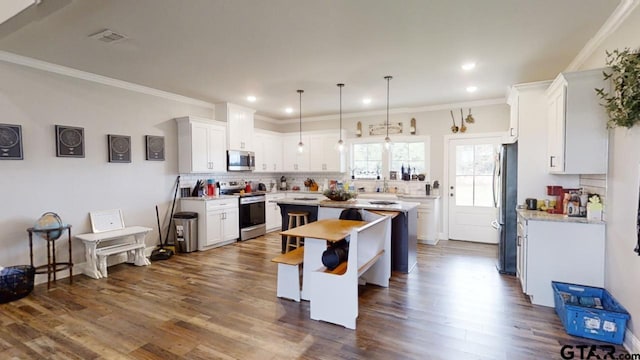 kitchen with decorative backsplash, white cabinets, appliances with stainless steel finishes, and a center island