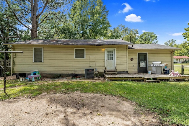 rear view of house with a deck, a lawn, and central AC