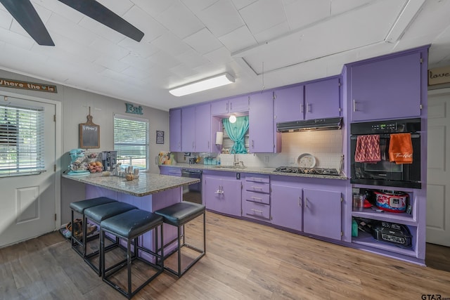 kitchen featuring sink, black appliances, a breakfast bar area, blue cabinetry, and light hardwood / wood-style flooring