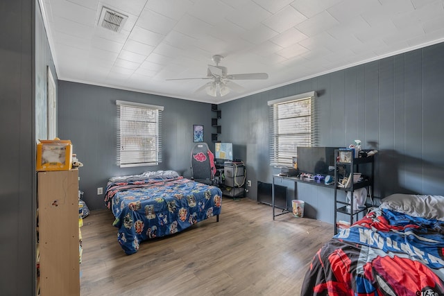 bedroom with hardwood / wood-style flooring, ceiling fan, multiple windows, and crown molding