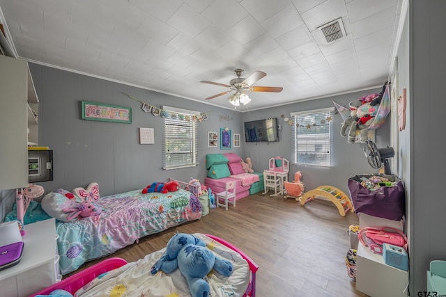 bedroom with ornamental molding, ceiling fan, multiple windows, and wood-type flooring