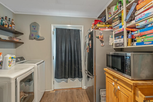 clothes washing area with washer and clothes dryer, light wood-type flooring, and crown molding