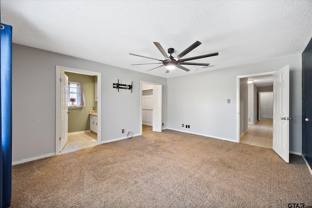 223 Guadalupe Dr, Athens, TX 75751 - unfurnished bedroom with light carpet, light tile patterned floors, baseboards, ensuite bathroom, and a textured ceiling