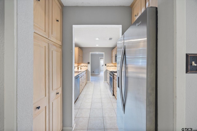 223 Guadalupe Dr, Athens, TX 75751 - kitchen featuring stainless steel appliances, light brown cabinets, light tile patterned floors, backsplash, and light countertops