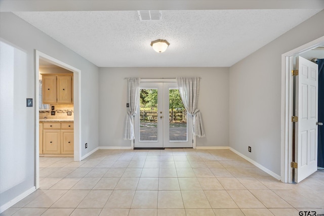 223 Guadalupe Dr, Athens, TX 75751 - unfurnished room with french doors, light tile patterned floors, baseboards, and a textured ceiling